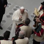 Pope Francis speaks to bagpipe players at the end of his weekly general audience in the Paul VI Hall, at the Vatican, Wednesday, Dec. 22, 2021. (AP Photo/Alessandra Tarantino)