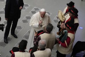 Pope Francis speaks to bagpipe players at the end of his weekly general audience in the Paul VI Hall, at the Vatican, Wednesday, Dec. 22, 2021. (AP Photo/Alessandra Tarantino)