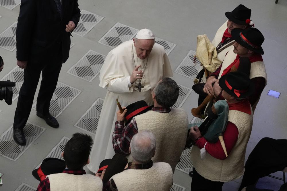 Pope Francis speaks to bagpipe players at the end of his weekly general audience in the Paul VI Hall, at the Vatican, Wednesday, Dec. 22, 2021. (AP Photo/Alessandra Tarantino)