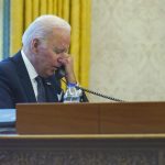 In this image made through a window, President Joe Biden talks on the phone with Ukrainian President Volodymyr Zelenskyy from the Oval Office of the White House in Washington, Thursday, Dec. 9, 2021. (AP Photo/Susan Walsh)