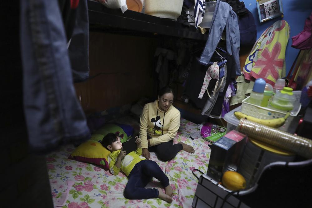 Noraida Gmama, 40, sits by her three-year-old undocumented daughter Aliha, in their small, shabby apartment shared with a half-dozen people, in Sharjah, United Arab Emirates, Monday, Dec. 6, 2021. Unmarried, she gave birth in secret at home and is now struggling to figure out how to document her toddler who cannot travel, enroll in school or go to a public hospital without a birth certificate. (AP Photo/Kamran Jebreili)