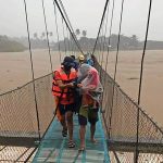 In this handout photo provided by the Philippine Coast Guard, rescuers assist residents cross a bridge as they are evacuated to higher grounds in Tubay town, Agusan del Norte, southern Philippines on Thursday, Dec. 16, 2021. Tens of thousands of people were being evacuated to safety in the southern and central Philippines as Typhoon Rai approached Thursday at a time when authorities were warning the public to avoid crowds after the first infections caused by the omicron strain of the coronavirus were reported in the country, officials said. (Philippine Coast Guard via AP)