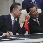 Chinese Foreign Minister Wang Yi, left, talks with Cambodian Prime Minister Hun Sen as they sit to witness a signing ceremony for a free trade agreement at Peace Palace in Phnom Penh, Cambodia, Monday, Oct. 12, 2020. The U.S. has ordered an arms embargo on Cambodia, citing deepening Chinese military influence, corruption and human rights abuses by the government and armed forces in the Southeast Asian country. (AP Photo/Heng Sinith, File)