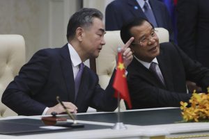 Chinese Foreign Minister Wang Yi, left, talks with Cambodian Prime Minister Hun Sen as they sit to witness a signing ceremony for a free trade agreement at Peace Palace in Phnom Penh, Cambodia, Monday, Oct. 12, 2020. The U.S. has ordered an arms embargo on Cambodia, citing deepening Chinese military influence, corruption and human rights abuses by the government and armed forces in the Southeast Asian country. (AP Photo/Heng Sinith, File)