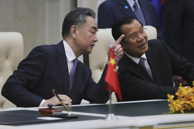 Chinese Foreign Minister Wang Yi, left, talks with Cambodian Prime Minister Hun Sen as they sit to witness a signing ceremony for a free trade agreement at Peace Palace in Phnom Penh, Cambodia, Monday, Oct. 12, 2020. The U.S. has ordered an arms embargo on Cambodia, citing deepening Chinese military influence, corruption and human rights abuses by the government and armed forces in the Southeast Asian country. (AP Photo/Heng Sinith, File)