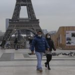 People wearing face masks to protect against COVID-19 cross the Trocadero Plaza in Paris, Wednesday, Dec. 15, 2021. Authorities in France want to accelerate vaccinations against the coronavirus before Christmas as infections surge and more people with COVID-19 seek medical attention. Eiffel Tower in the background. (AP Photo/Michel Euler)