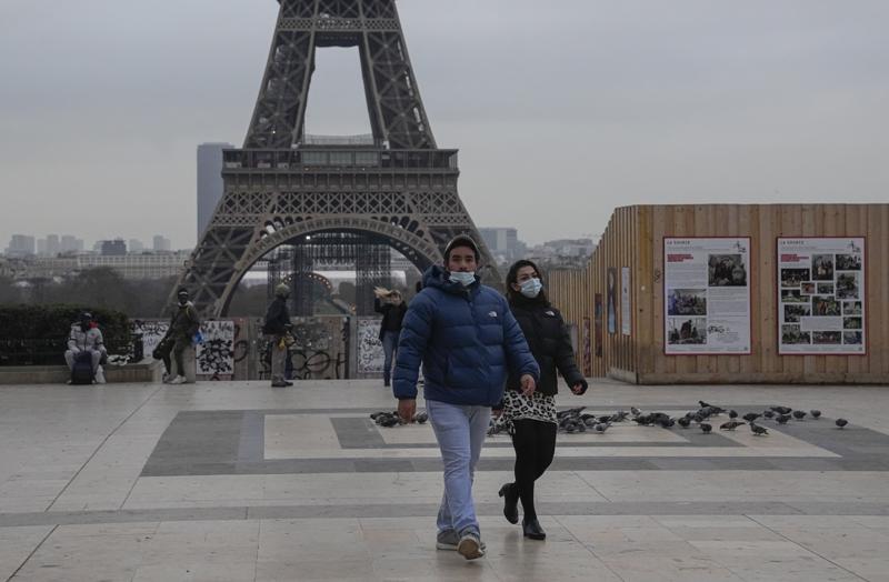 People wearing face masks to protect against COVID-19 cross the Trocadero Plaza in Paris, Wednesday, Dec. 15, 2021. Authorities in France want to accelerate vaccinations against the coronavirus before Christmas as infections surge and more people with COVID-19 seek medical attention. Eiffel Tower in the background. (AP Photo/Michel Euler)