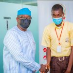 Ekiti State Governor Kayode Fayemi (L) receives best performing student Ikeoluwa Okunola (R)