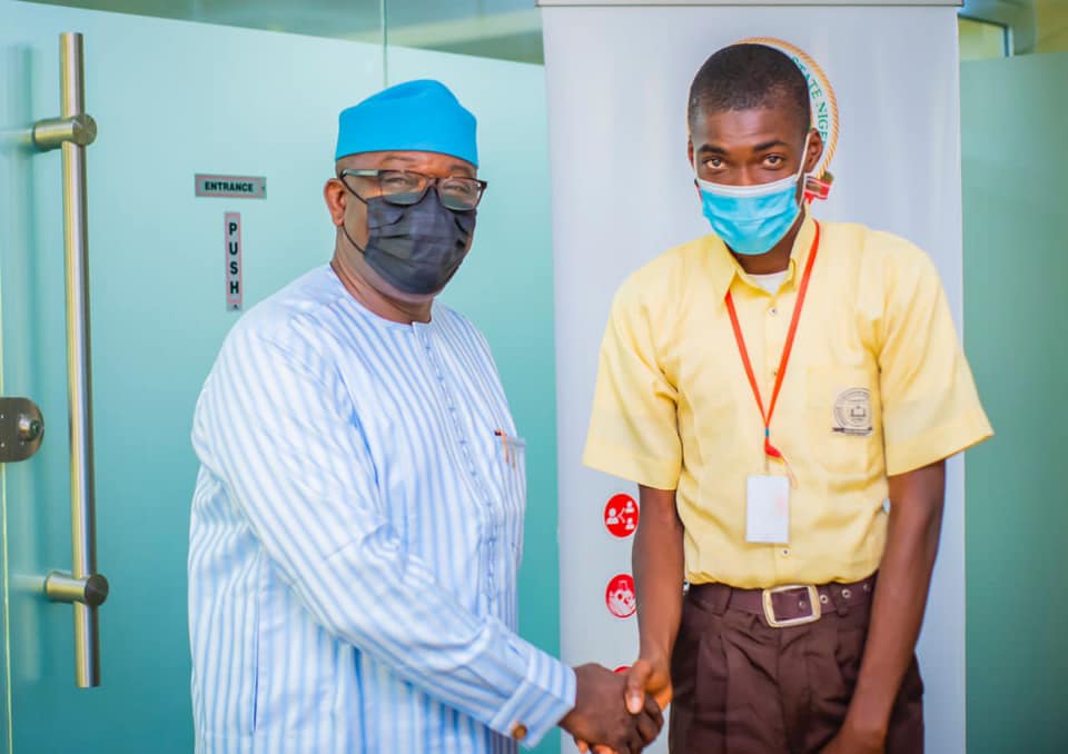 Ekiti State Governor Kayode Fayemi (L) receives best performing student Ikeoluwa Okunola (R)
