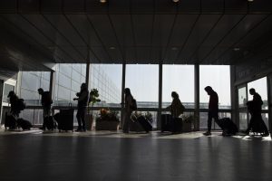 FILE – Travelers walk with their luggage in the Ben Gurion Airport near Tel Aviv, Israel, Sunday, Nov. 28, 2021. Israeli ministers on Monday agreed to ban travel to the United States, Canada and eight other countries amid the rapid, global spread of the omicron variant. (AP Photo/Ariel Schalit, File)