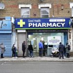 People wait in line to receive a ‘Jingle Jab’ Covid vaccination booster injection at the Good Health Pharmacy, north London, Saturday, Dec. 25, 2021. Thousands of people across England are spending a few minutes of Christmas Day to line up under leaden winter skies to be vaccinated against COVID-19 as the omicron variant fuels a surge in infections across the country. The Good Health Pharmacy in north London is one of dozens of vaccination sites that kept their doors open Saturday to administer “jingle jabs” amid a government push to offer booster shots to all adults by the end of the year. (Gareth Fuller/PA via AP)