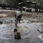 A man collects polluted water at an illegal oil refinery site near river Nun in Nigeria’s oil state of Bayelsa