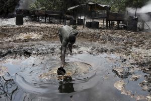 A man collects polluted water at an illegal oil refinery site near river Nun in Nigeria’s oil state of Bayelsa