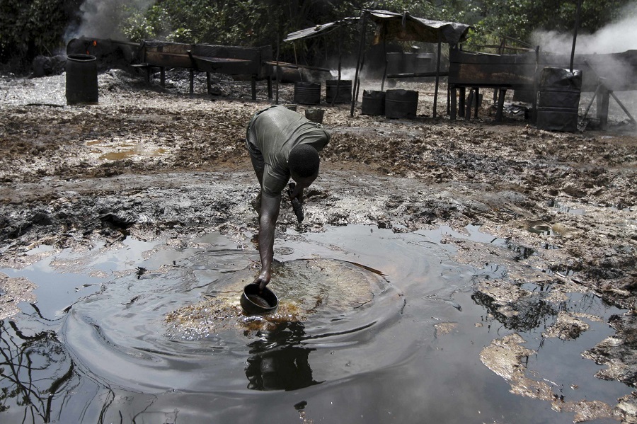 A man collects polluted water at an illegal oil refinery site near river Nun in Nigeria’s oil state of Bayelsa