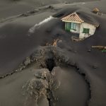 FILE – A fissure is seen next to a house covered with ash on the Canary island of La Palma, Spain, Dec. 1 2021. Authorities on a Spanish island are declaring a volcanic eruption that has caused widespread damage but no casualties officially finished, following ten days of no significant sulfur dioxide emissions, lava flows or seismic activity. But the emergency in La Palma, the northwesternmost of the Atlantic Ocean’s Canary Islands, is not over yet, said the director of the archipelago’s volcanic emergency committee, or Pevolca, Julio Pérez. (AP Photo/Emilio Morenatti, File)