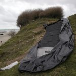 FILE – A damaged inflatable small boat is pictured on the shore in Wimereux, northern France, Thursday, Nov. 25, 2021 in Calais, northern France. The Paris prosecutor’s office said it has received a manslaughter lawsuit for failure to help in the tragic capsizing last month of a boat in the English Channel that cost the lives of at least 27 people trying to reach Britain. The manslaughter lawsuit, filed Friday, Dec. 17, 2021 by the French humanitarian organization Utopia 56, accuses the maritime prefect of the Channel and North Sea, the Regional Operational Centre for Surveillance and Rescue of Gris-Nez in the Pas-de-Calais and the British Coast Guard of not doing enough to prevent the deaths. (AP Photo/Michel Spingler, File)