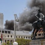 Firemen spray water on flames erupting from a building at South Africa’s Parliament in Cape Town Sunday Jan. 2, 2022. (AP Photo/Jerome Delay)