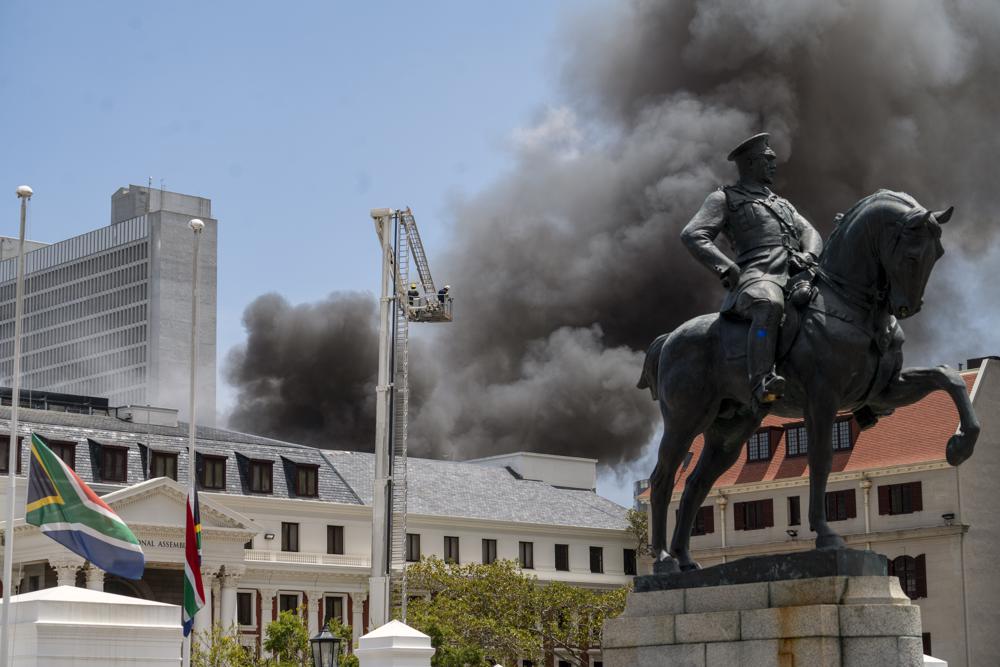 Firemen spray water on flames erupting from a building at South Africa’s Parliament in Cape Town Sunday Jan. 2, 2022. (AP Photo/Jerome Delay)