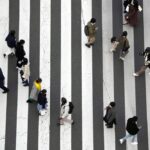 People wearing protective masks to help curb the spread of the coronavirus walk along a pedestrian crossing Monday, Jan. 17, 2022, in Tokyo. (AP Photo/Eugene Hoshiko)