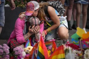 People react laying flowers at the scene of a shooting in central Oslo, Norway, Saturday, June 25, 2022. Norwegian police say they are investigating an overnight shooting in Oslo that killed two people and injured more than a dozen as a case of possible terrorism. In a news conference Saturday, police officials said the man arrested after the shooting was a Norwegian citizen of Iranian origin who was previously known to police but not for major crimes. (AP Photo/Sergei Grits)