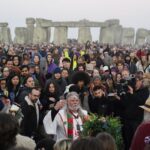 Arthur Uther Pendragon, center, joins people as they gather at the Heel Stone during sunrise for the Summer Solstice festivities at Stonehenge in Wiltshire, England, Tuesday, June 21, 2022. After two years of closure due to the COVID-19 pandemic, Stonehenge reopened Monday for the Summer Solstice celebrations. (Andrew Matthews/PA via AP)