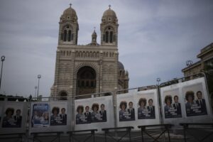 Campaign posters hang in front of the Cathedral of Saint Mary Major in Marseille, southern France, Thursday, June 16, 2022. President Emmanuel Macron urged the French to give him a “strong majority” Sunday in the second, decisive round of nationwide parliamentary elections. (AP Photo/Daniel Cole)