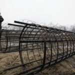 FILE-Guards and the military watching the start of work on the first part of a 180 kilometers (115 miles) and 5.5 meter (18ft)-high metal wall intended to block migrants from Belarus crossing illegally into EU territory, in Tolcze, near Kuznica, Poland, Jan. 27, 2022. A year after migrants started crossing into the European Union from Belarus to Poland, Polish authorities are planning to announce Thursday that a 5.5-meter-tall steel wall along its border to the north with Belarus is set to be completed. (AP Photo/Czarek Sokolowski, File)