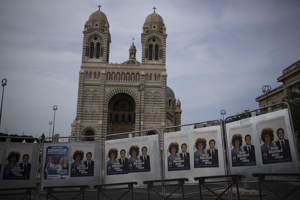 Campaign posters hang in front of the Cathedral of Saint Mary Major in Marseille, southern France, Thursday, June 16, 2022. President Emmanuel Macron urged the French to give him a “strong majority” Sunday in the second, decisive round of nationwide parliamentary elections. (AP Photo/Daniel Cole)