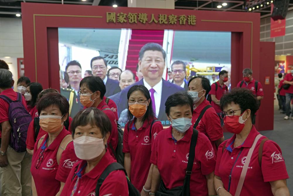 Visitors walk in front of a TV showing Chinese president Xi Jinping at an exhibition to celebrate the 25th anniversary of Hong Kong handover to China in Hong Kong, Friday, June 24, 2022. President Xi Jinping will participate in next week’s celebrations of the 25th anniversary of the return of Hong Kong to China, the government said Saturday, but it left unclear whether he will visit the former British colony for the highly symbolic event after a crackdown on a pro-democracy movement. (AP Photo/Kin Cheung)