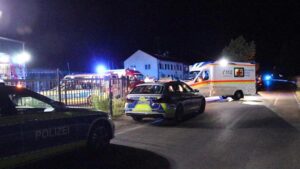 In this video still imgage police and emergency services stand at an asylum seeker shelter after a knife attack in Kressbronn, Germany, Sunday, June 26, 2022. A knife-wielding attacker has stabbed several people in a shelter for asylum-seekers in southern Germany, killing one man and wounding at least five people. (Davor Knappmeyer/dpa via AP)