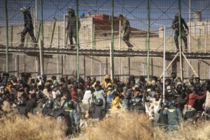 FILE – Riot police officers cordon off the area after migrants arrive on Spanish soil and crossing the fences separating the Spanish enclave of Melilla from Morocco in Melilla, Spain, on June 24, 2022. Spain’s prime minister on Monday, June 27, 2022, defended the way Moroccan and Spanish police repelled migrants the week before as they tried to cross the shared border into the north African enclave of Melilla, depicting the attempt in which at least 23 people died as “an attack on Spain’s borders.” (AP Photo/Javier Bernardo, File)