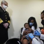 Pediatrician Emy Jean-Marie, center, holds her nine-month-old son Adedeji Adebayo, Emiola Adebayo, 3, on her lap as Dr. Nizar Dowla, right, administers a vaccine while        Department of Health and Human Services Assistant Secretary for Health, Admiral Rachel Levine, left, looks on, Tuesday, June 28, 2022, at the Borinquen Health Care Center in Miami. Florida is the only state that didn’t pre-order the under-5 vaccine, and state Surgeon General Joseph Ladapo has recommended against vaccinating healthy children. (AP Photo/Wilfredo Lee)