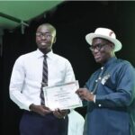 Adegbulugbe (R) presenting a scholarship award to a recepient from Ikuru town