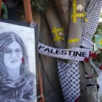 Yellow tape marks bullet holes on a tree and a portrait and flowers create a makeshift memorial on o May 19, 2022, at the site where Palestinian-American Al-Jazeera journalist Shireen Abu Akleh was shot and killed in the West Bank city of Jenin. The Palestinian Authority on Saturday, July 2, 2022, said it has given the bullet that killed Al Jazeera journalist Shireen Abu Akleh to American forensic experts, taking a step toward resolving a standoff with Israel over the investigation into her death. (AP Photo/Majdi Mohammed)