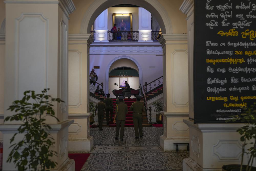 Police officers walk inside the official residence of President Gotabaya Rajapaksa in in Colombo, Sri Lanka, Thursday, July 14, 2022. With the country sinking into political chaos, Rajapaksa and his wife fled to the Maldives on Wednesday aboard an air force jet. He made the prime minister acting president in his absence — a move that further roiled passions among a public that blames Rajapaksa for an economic crisis that has caused severe shortages of food and fuel. (AP Photo/Rafiq Maqbool)