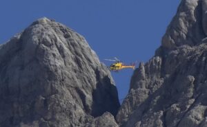 A rescue helicopter hovers over the Punta Rocca glacier near Canazei, in the Italian Alps in northern Italy, Monday, July 4, 2022, a day after a huge chunk of the glacier broke loose, sending an avalanche of ice, snow, and rocks onto hikers. Rescuers said conditions downslope from the glacier, which has been melting for decades, were still too unstable to immediately send rescuers and dogs into the area to look for others buried under tons of debris. (AP Photo/Luca Bruno)