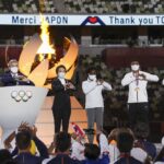 FILE – International Olympic Committee’s President Thomas Bach and Seiko Hashimoto, president of the Tokyo Organizing Committee of the Olympic and Paralympic Games make the sign of a heart with their hands during the closing ceremony in the Olympic Stadium at the 2020 Summer Olympics, Sunday, Aug. 8, 2021, in Tokyo, Japan. The Tokyo Olympics survived the COVID-19 postponement, soaring expenses and some public opposition. A year later, the costs and benefits are as difficult to untangle as the Games were to pull off. (Dan Mullen/Pool Photo via AP)