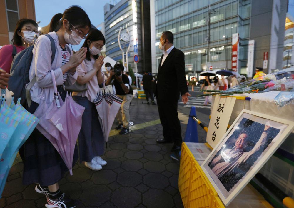 A photo of former Prime Minister Shinzo Abe is displayed on a makeshift memorial near the scene where Abe was fatally shot while delivering his speech to support a Liberal Democratic Party’s candidate on Friday, in Nara, Saturday, July 9, 2022. (Yosuke Mizuno/Kyodo News via AP)