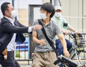 FILE – Tetsuya Yamagami, center, holding a weapon, is detained near the site of gunshots in Nara, western Japan, Friday, July 8, 2022. The 40-centimeter-long (16-inch) firearm that was used to kill former Prime Minister Shinzo Abe on Friday as he campaigned for his ruling party in Nara, western Japan, looked crude, more like a propellant made of pipes taped together and filled with explosives. (Nara Shimbun/Kyodo News via AP, File)