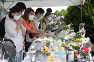People offer prayers near the site of the fatal shooting of former Japanese Prime Minister Shinzo Abe, in Nara, western Japan Saturday, July 9, 2022. Public outrage, handwringing and vows of defiance in media and among political commentators are widespread in Japan following the daylight assassination of Abe. (Kyodo News via AP)