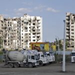 Cement trucks parked at a construction site of an apartment building under construction for residents of Mariupol affected by hostilities, in Mariupol, in territory under the government of the Donetsk People’s Republic, eastern Ukraine, Friday, July 1, 2022. (AP Photo)