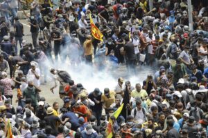 Protesters react as a tear gas shell fired by police lands next to them in Colombo, Sri Lanka, Saturday, July 9, 2022. Sri Lankan protesters demanding that President Gotabaya Rajapaksa resign forced their way into his official residence on Saturday, a local television report said, as thousands of people took to the streets in the capital decrying the island nation’s worst economic crisis in recent memory. (AP Photo/Amitha Thennakoon)