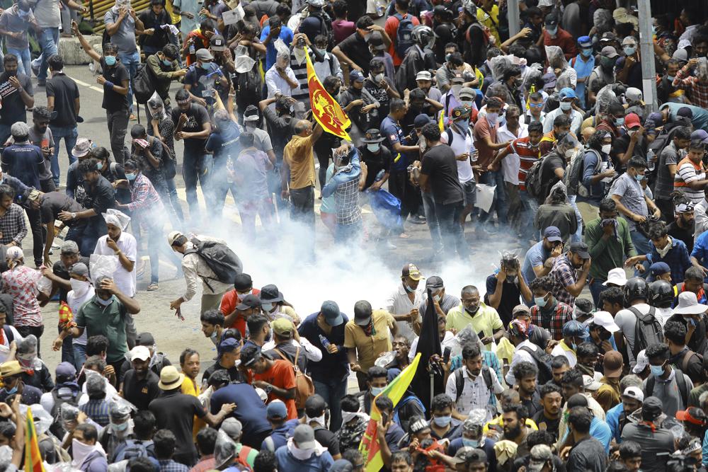 Protesters react as a tear gas shell fired by police lands next to them in Colombo, Sri Lanka, Saturday, July 9, 2022. Sri Lankan protesters demanding that President Gotabaya Rajapaksa resign forced their way into his official residence on Saturday, a local television report said, as thousands of people took to the streets in the capital decrying the island nation’s worst economic crisis in recent memory. (AP Photo/Amitha Thennakoon)
