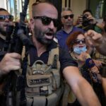 Lebanese State Security forces surround Lebanese Judge Ghada Aoun, wearing face mask, as she leaves the entrance of Central Bank following a raid to pursue Central Bank Governor Riad Salameh, who she has charged for corruption in Beirut, Lebanon, Tuesday, July 19, 2022. (AP Photo/Bilal Hussein)