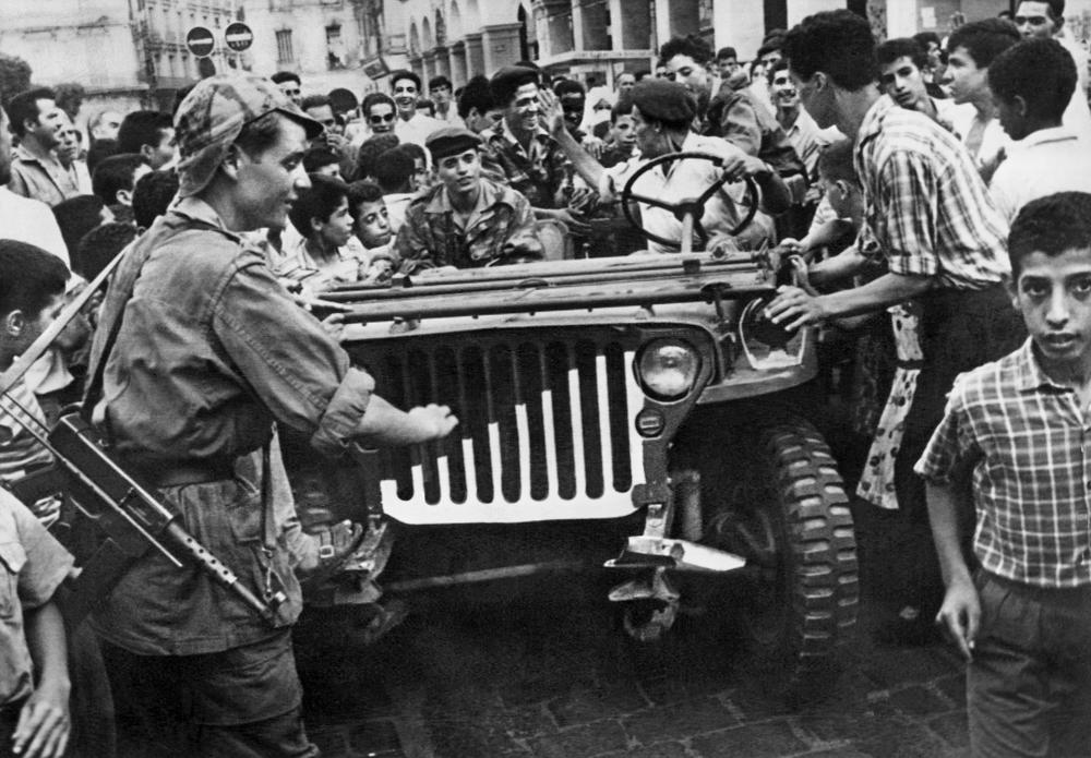 FILE – A jeep of the Algerian Liberation Front (FLN) is surrounded by an enthusiastic crowd in Algiers, Algeria, in July 1962. Algeria is celebrating 60 years of independence from France on Tuesday July 5, 2022 with nationwide ceremonies, a pardon of 14,000 prisoners and its first military parade in years. Tuesday’s events mark 60 years since the official declaration of independence on July 5, 1962, after a brutal seven-year war which ended 132 years of colonial rule. The war, which killed at least 1.5 million people, remains a point of tension in relations between Algeria and France. (AP Photo, File)