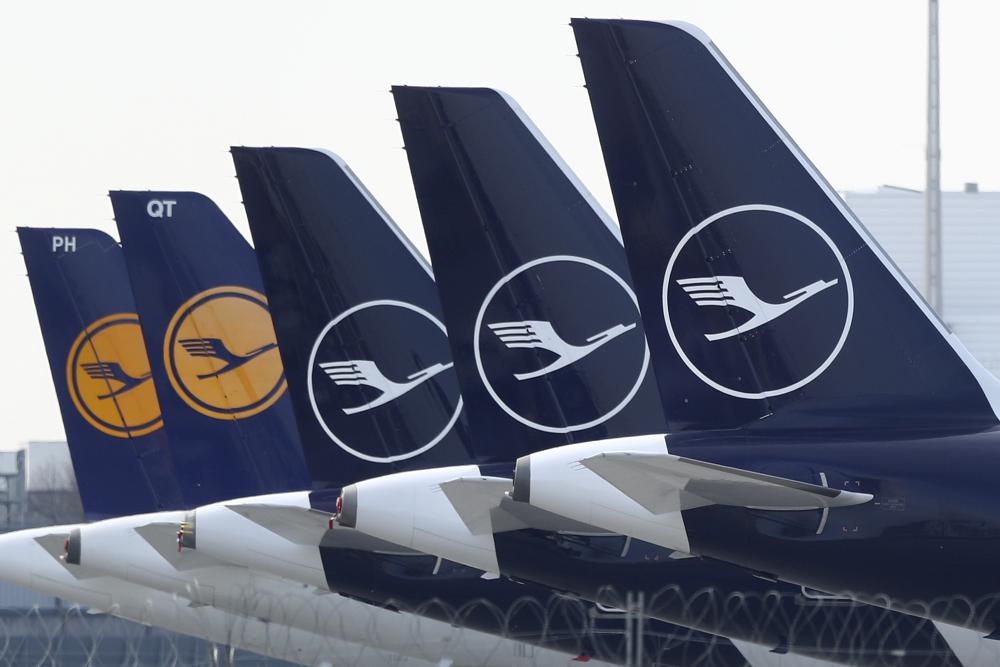 FILE –German Lufthansa planes sit parked in a line at the airport in Munich, Germany, Thursday, March 26, 2020. Lufthansa says it will have to cancel almost all flights at its main Frankfurt and Munich hubs on Wednesday because of a strike by its German ground staff. (AP Photo/Matthias Schrader),file)