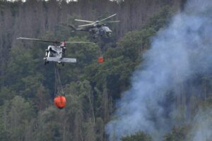 Helicopters carrying water to extinguish a wildfire in the area of the Ceske Svycarsko , Czech Switzerland, National Park, in Hrensko, Czech Republic, Wednesday, July 27, 2022.  (Ondrej Hajek/CTK via AP)