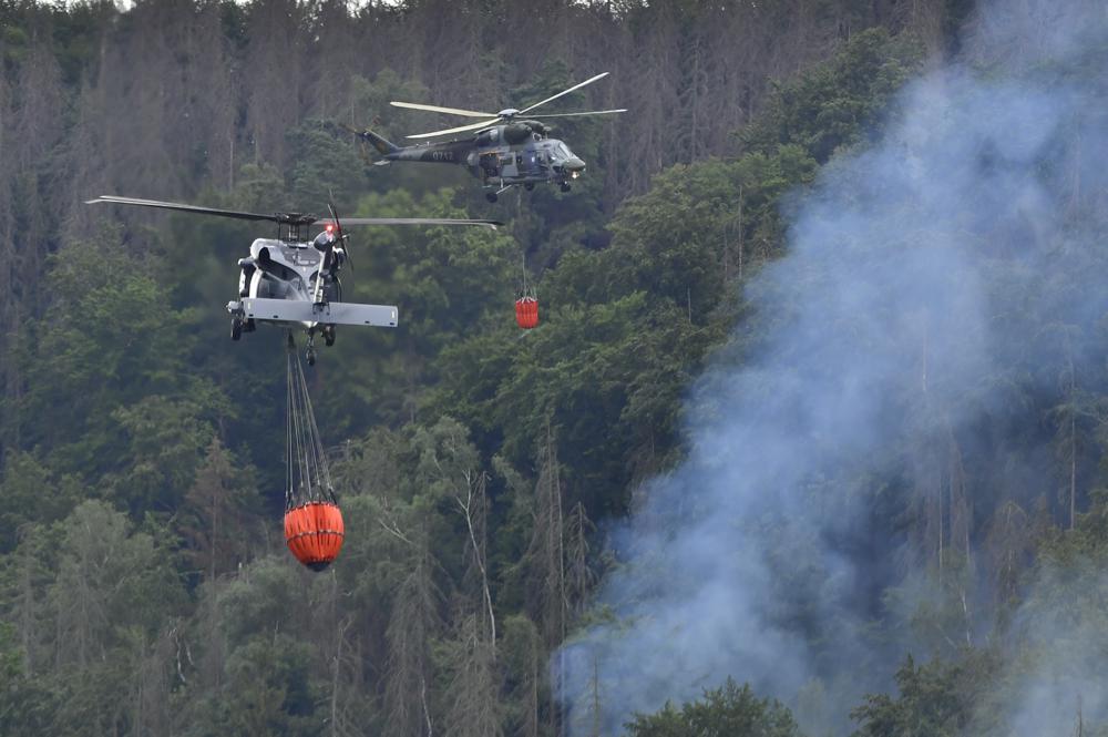 Helicopters carrying water to extinguish a wildfire in the area of the Ceske Svycarsko , Czech Switzerland, National Park, in Hrensko, Czech Republic, Wednesday, July 27, 2022.  (Ondrej Hajek/CTK via AP)