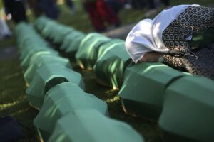 A Bosnian muslim woman mourns next to the coffin containing remains of her family member who is among 50 newly identified victims of Srebrenica Genocide in Potocari, Monday, July 11, 2022. Thousands converge on the eastern Bosnian town of Srebrenica to commemorate the 27th anniversary on Monday of Europe’s only acknowledged genocide since World War II. (AP Photo/Armin Durgut)