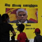 People watch propaganda materials displayed against prime minister Ranil Wickremesinghe outside president Gotabaya Rajapaksa’s office three days after it was stormed by anti government protesters in Colombo, Sri Lanka, Tuesday, July 12, 2022. (AP Photo/Eranga Jayawardena)